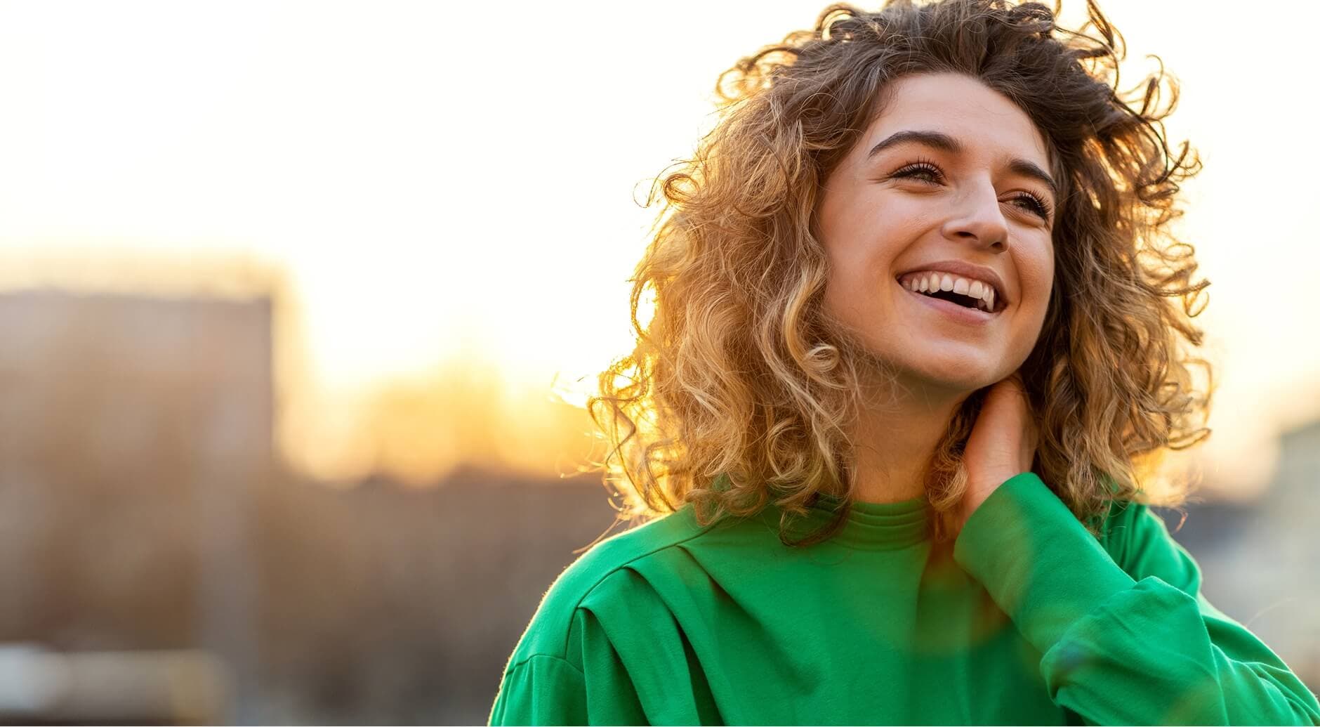 Woman smiling confidently outdoors at sunset, representing a positive outlook on naltrexone treatment