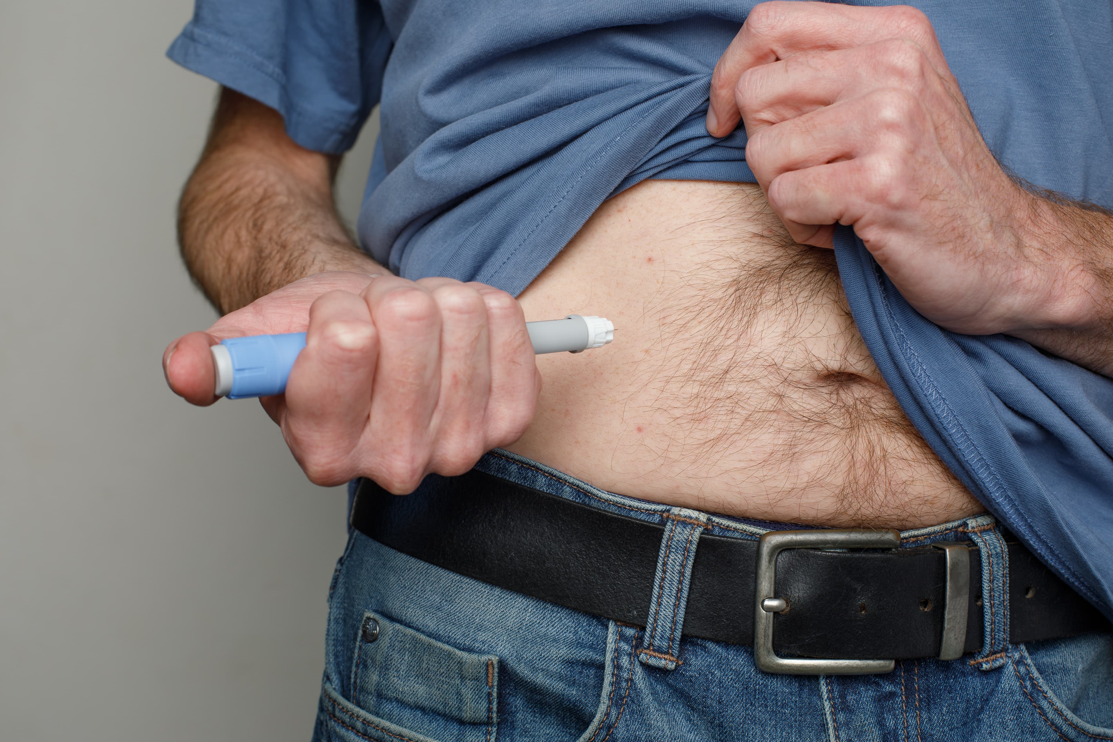 A man injecting himself in the belly with Ozempic