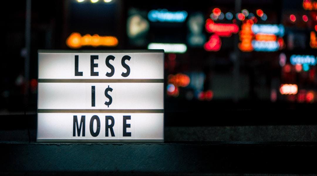 Close-up shot of a white sign that says "LESS IS MORE" in black letters.
