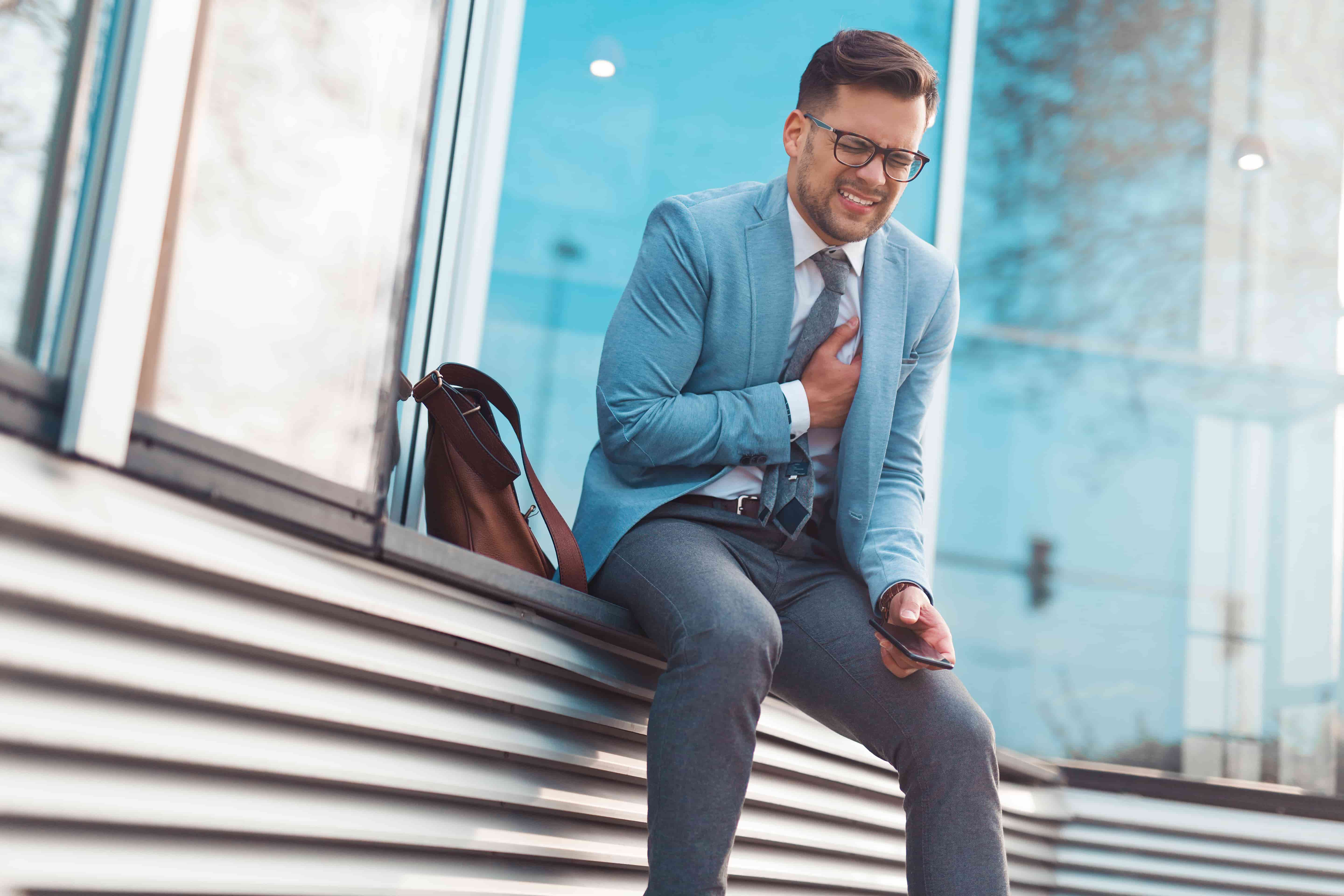 Alcohol and your heart - happy hour and hypertension. A man in a suit with chest pains.