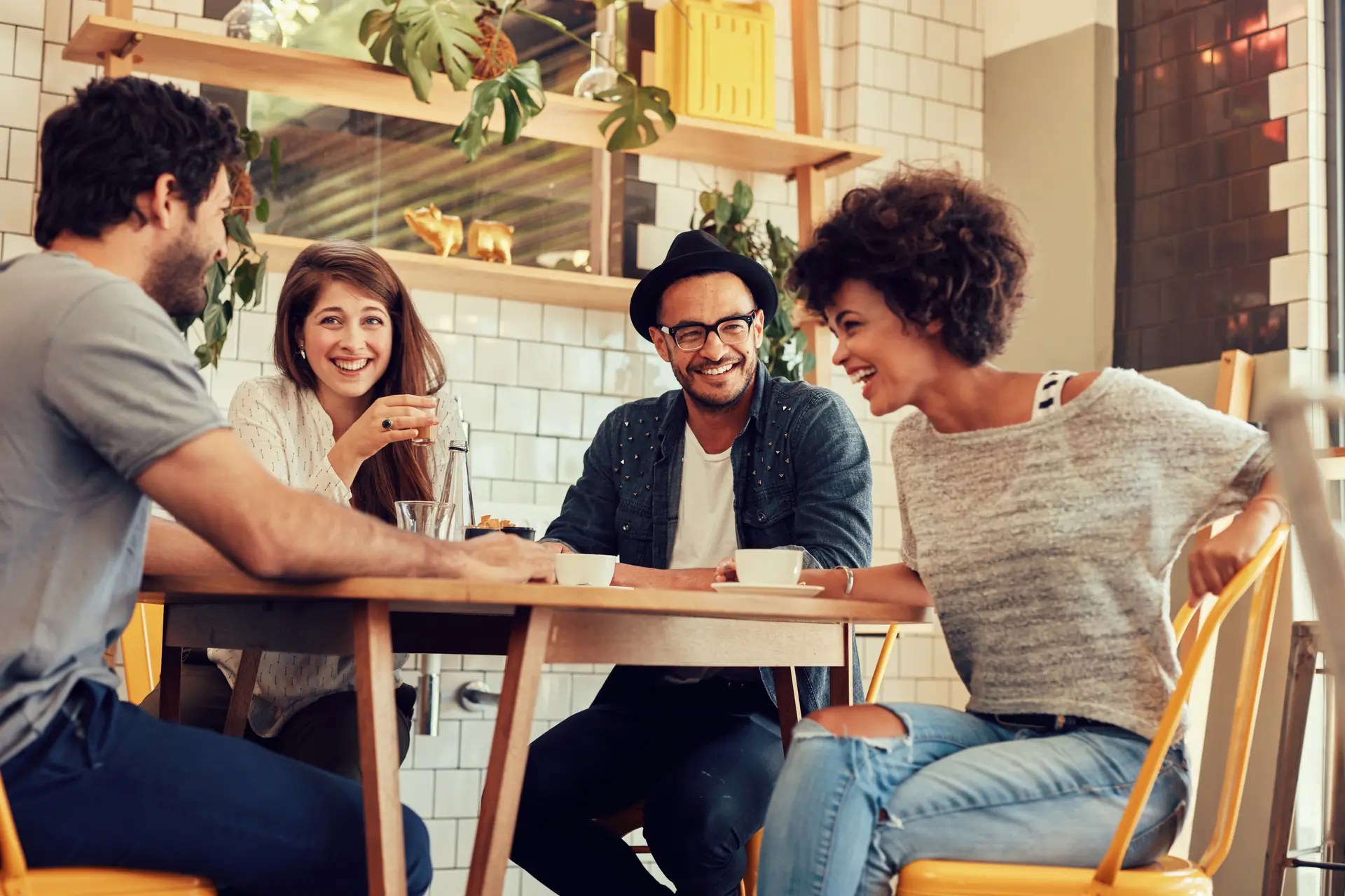 A group of men and women sitting around a table with coffee, laughing together.