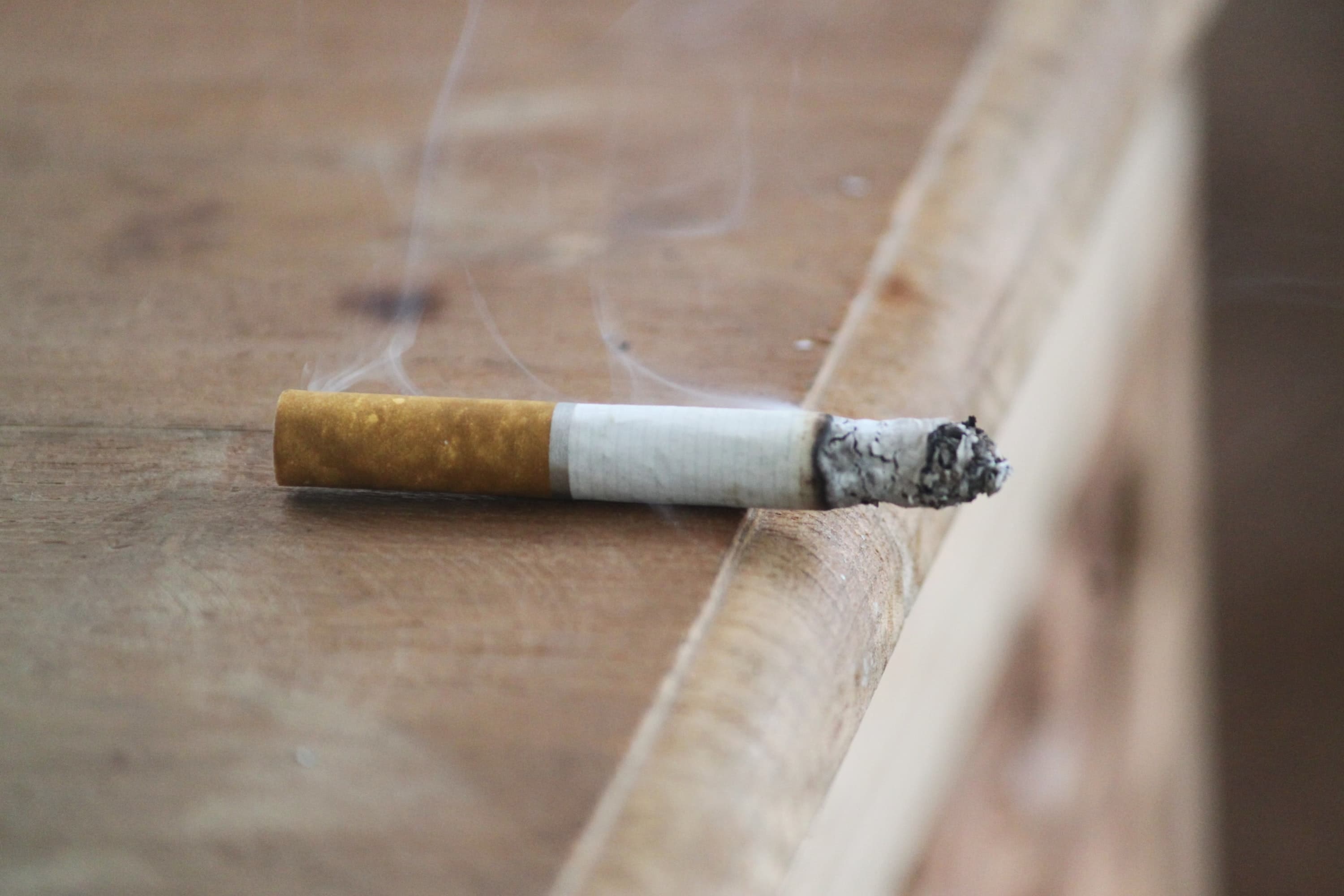 A lit cigarette rests on the edge of a table.
