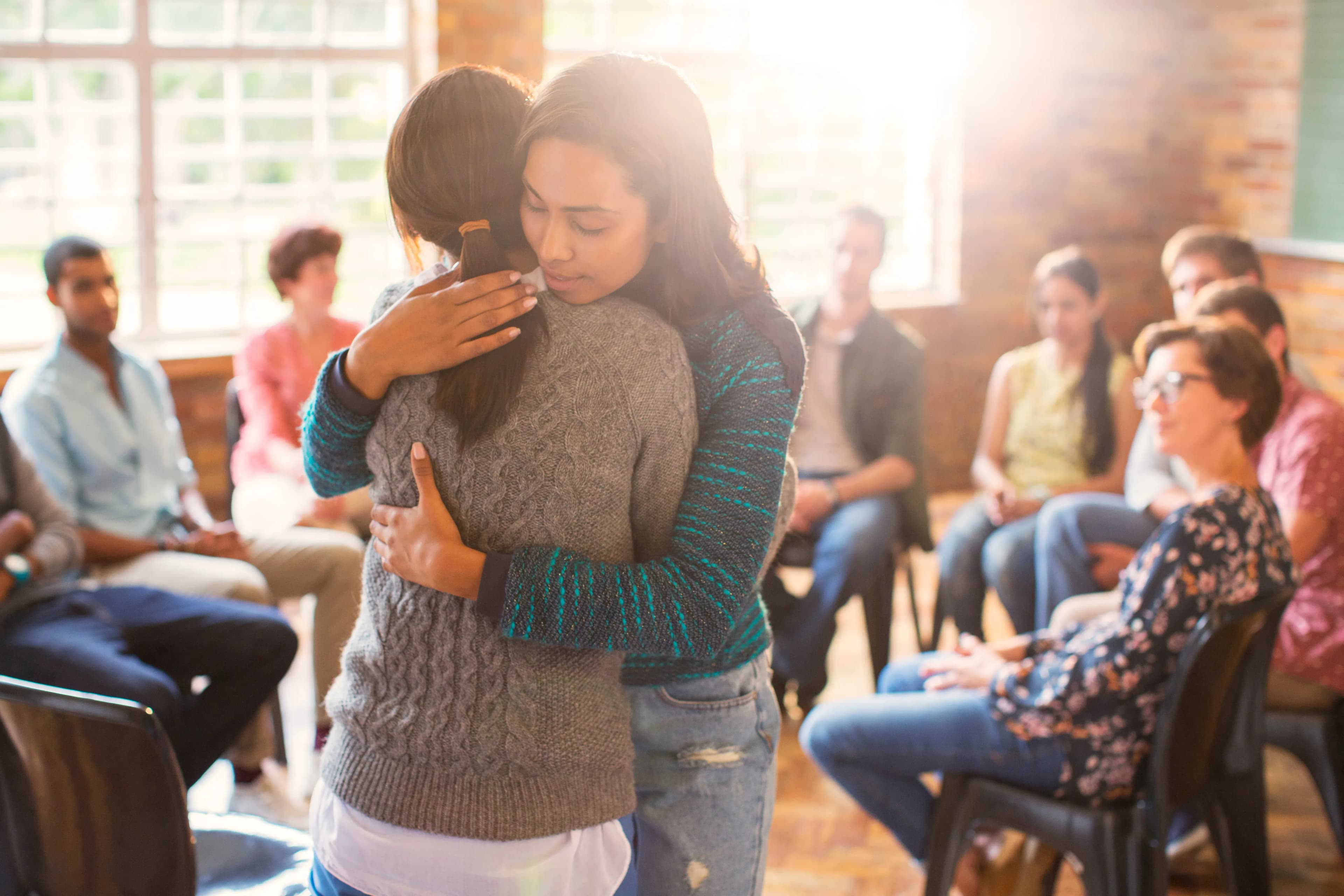 Alcohol treatment centers near me. Two women hugging during group therapy.