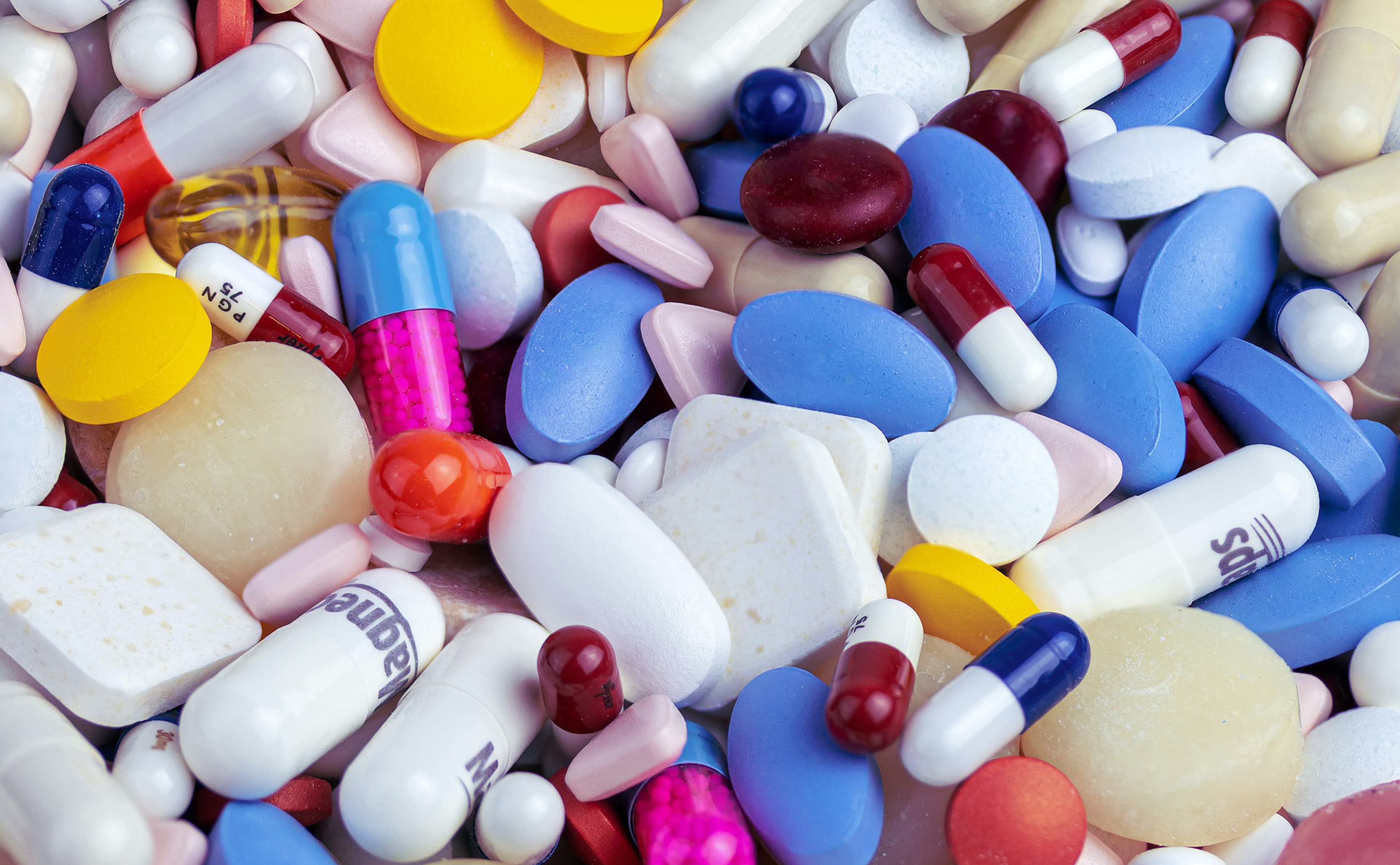 A close-up of several different kinds of brightly colored medication pills and capsules.