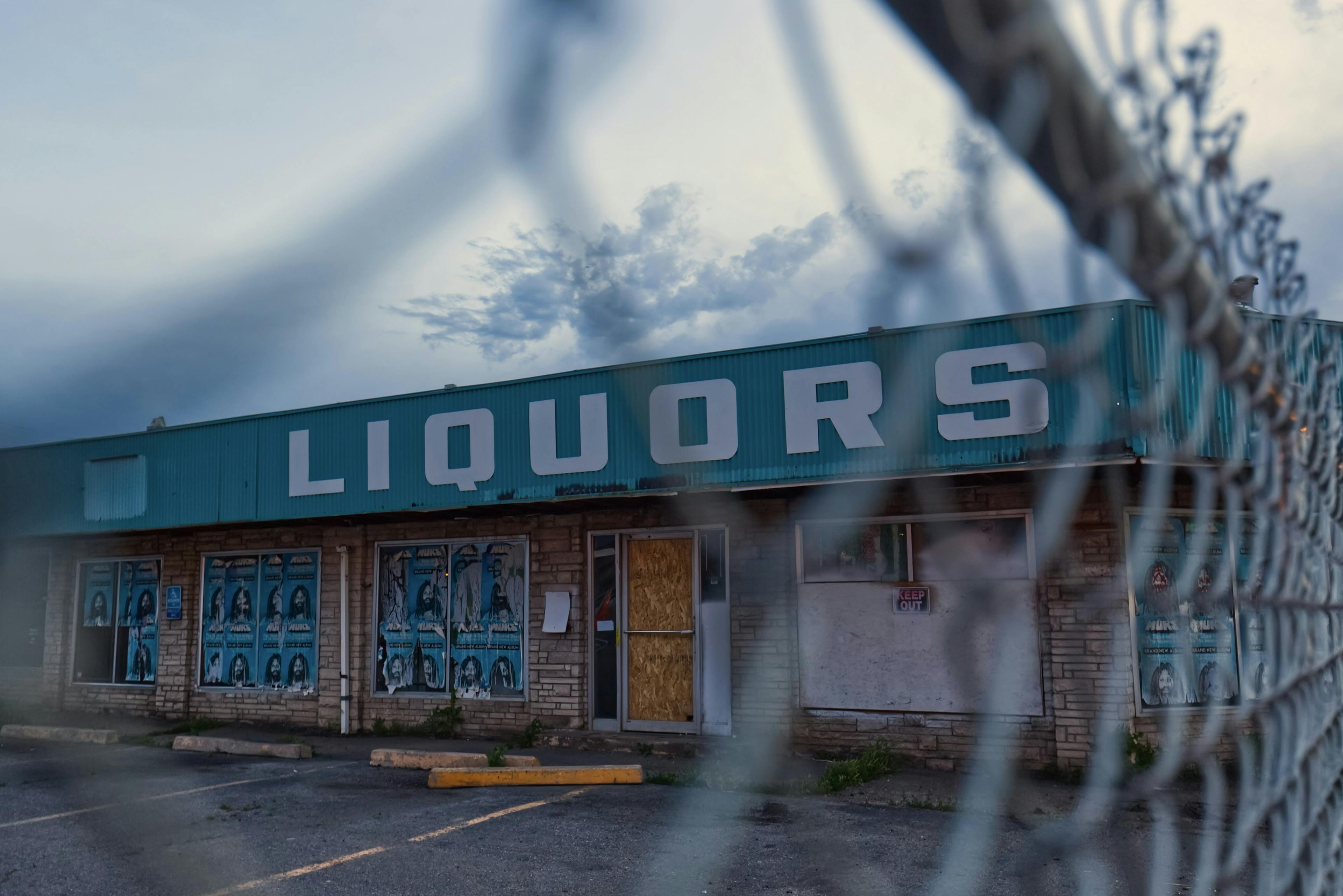 The outside of a liquor store is seen through a chain link fence.