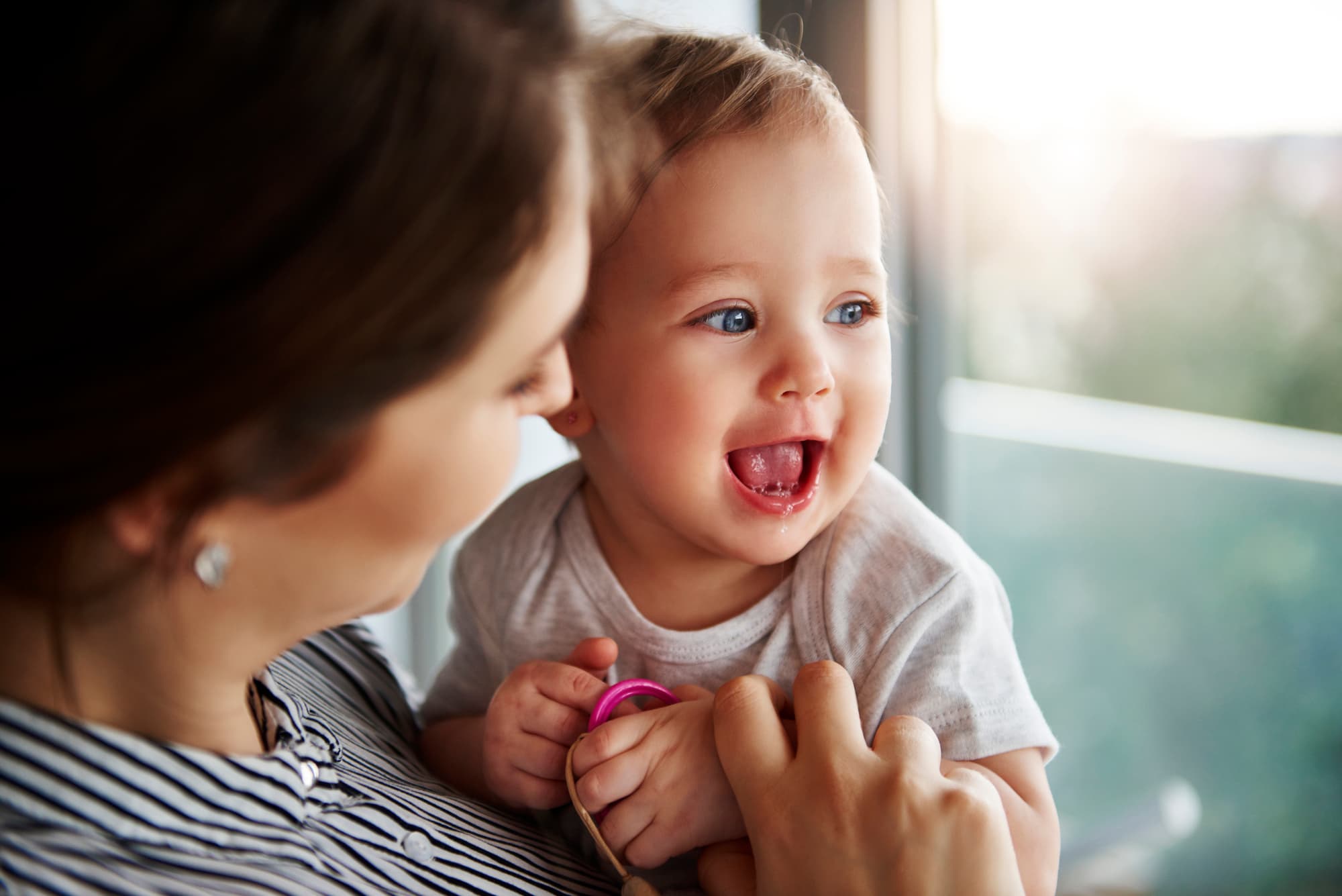 A closeup of a single parent as they hold their smiling baby.