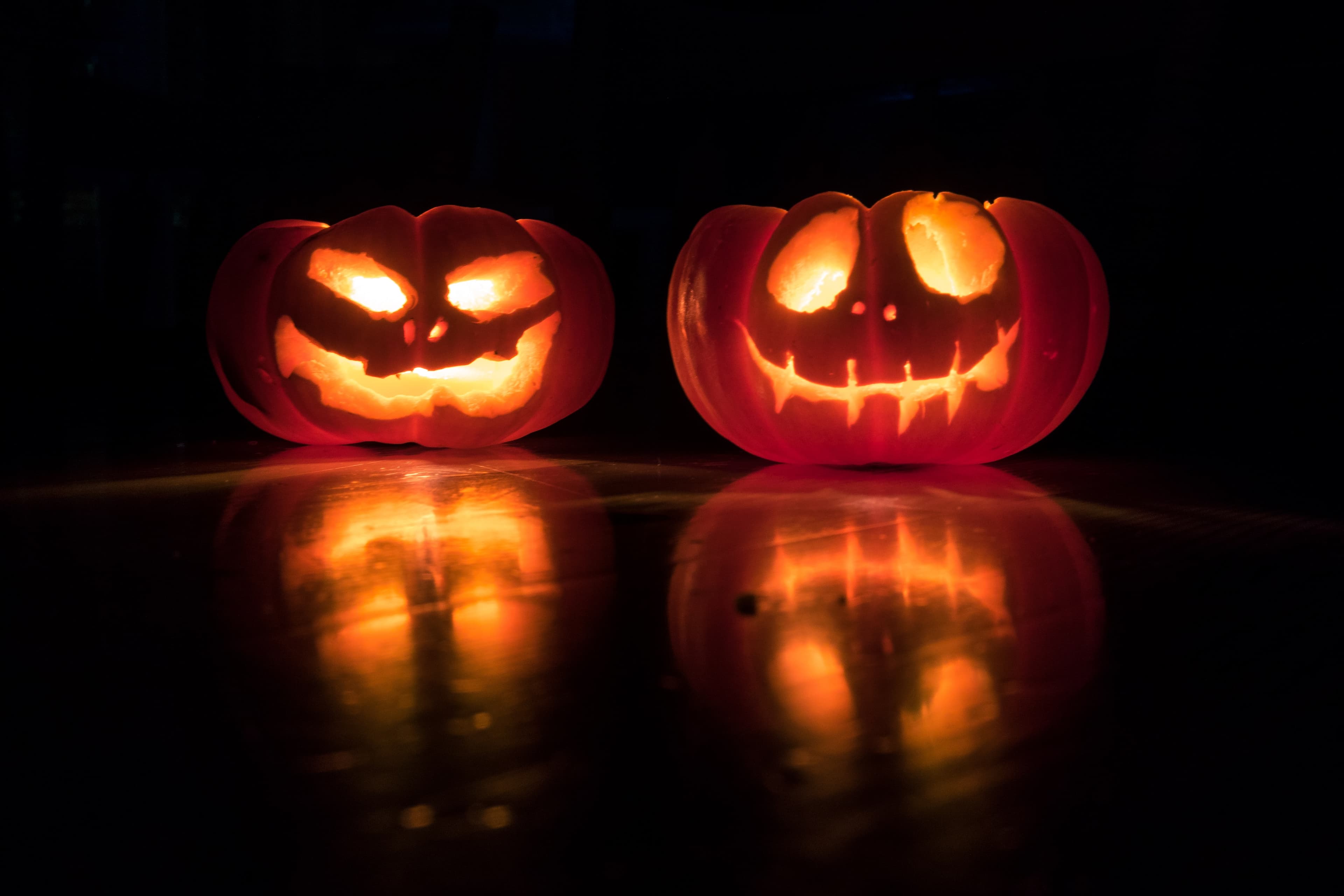 Two lit jack-o-lanterns against a black background.